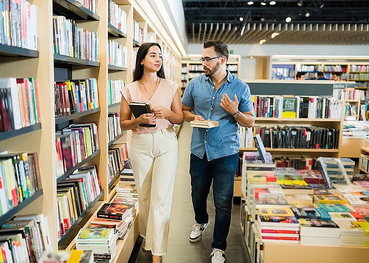 A young woman and man walking together at a bookstore and shopping for books.