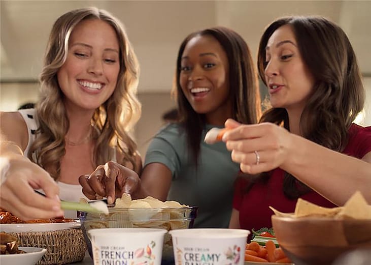 A group of women eating chips with french onion dip.