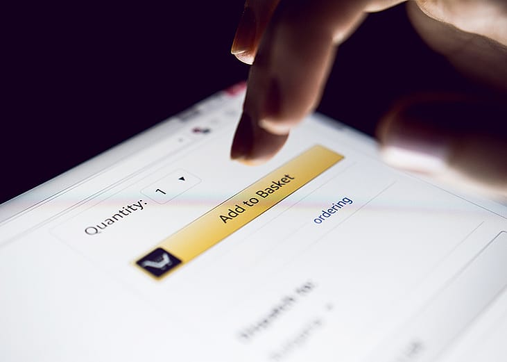 Person about to tap 'Add to basket' button on a shopping app.