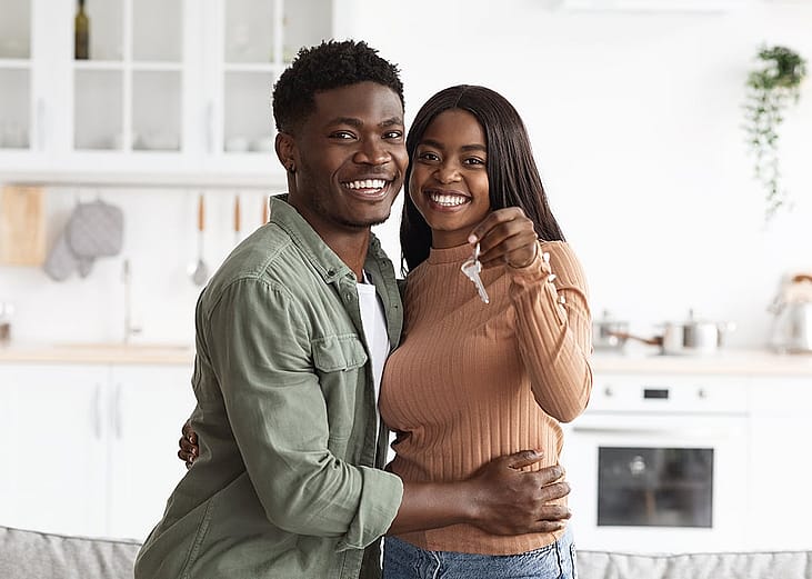 A young black couple happily holding keys to new home.