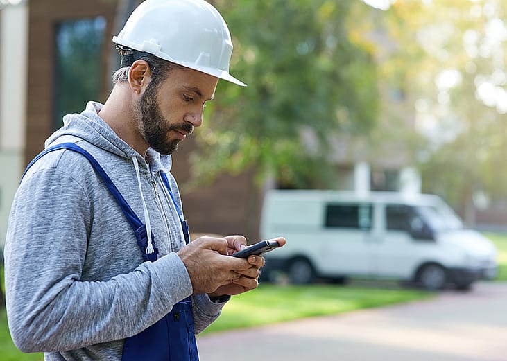A male construction worker checking phone outdoors.