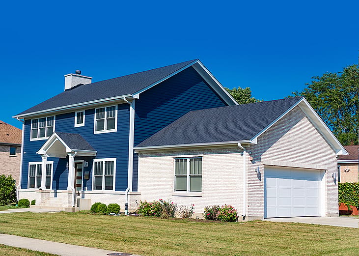 A blue and white modern, suburban home in a residential neighborhood.