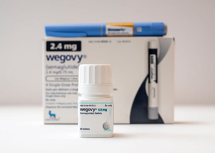 A bottle of Wegovy tablets its box and an Ozempic pen in the background.