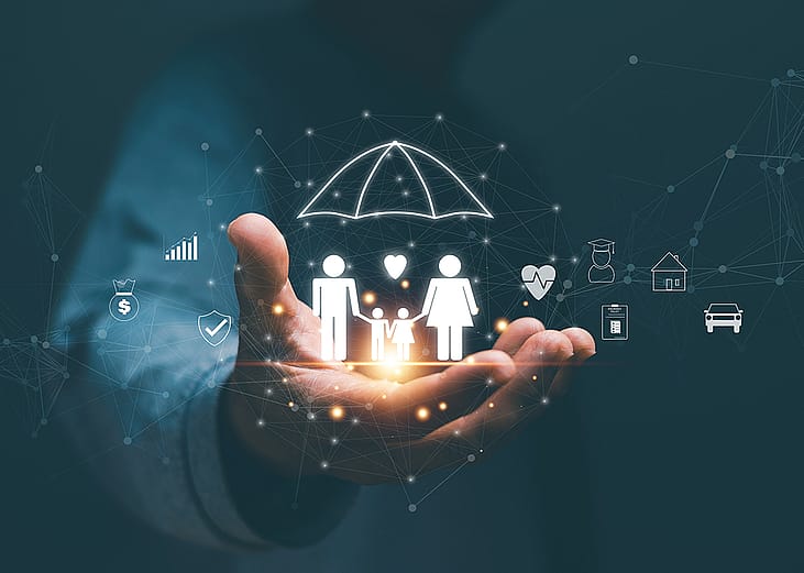 Person's hand holding hologram graphics of a family with an umbrella as a concept of life insurance.