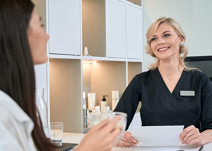A young woman consulting with a dermatologist at the reception bar of a spa.