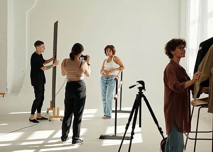 A creative team photographing a fashion model in a studio.