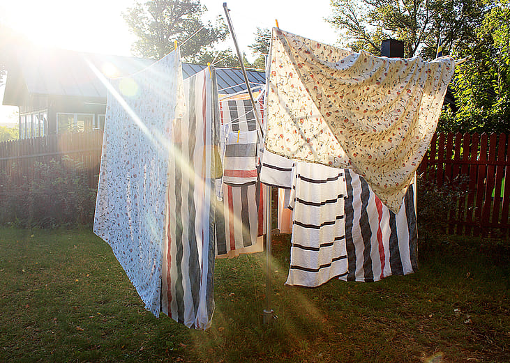 Washed sheets hanging from clothesline to dry under the sun.