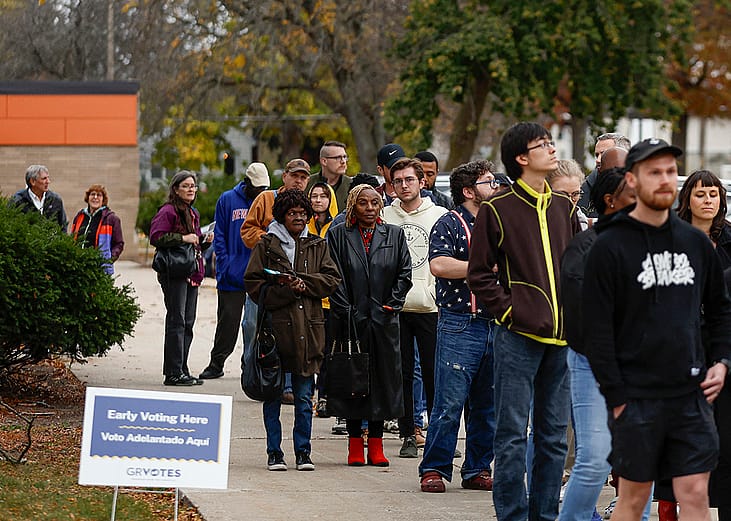 People wait in line to vote during early voting for the 2024 US general election at a polling station at Ottawa Hills High School in Grand Rapids, Michigan.