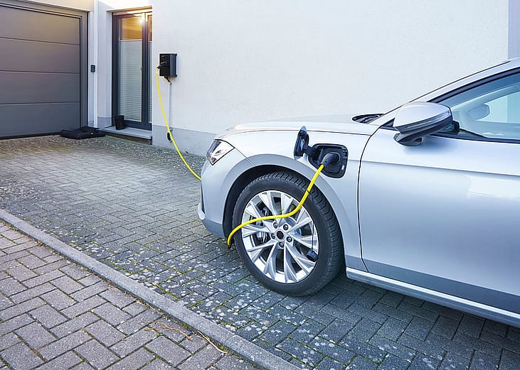 A car connected to an EV charger at home installed in the driveway.