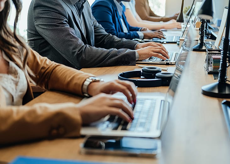 Businesspeople's hands on their laptop keyboards.
