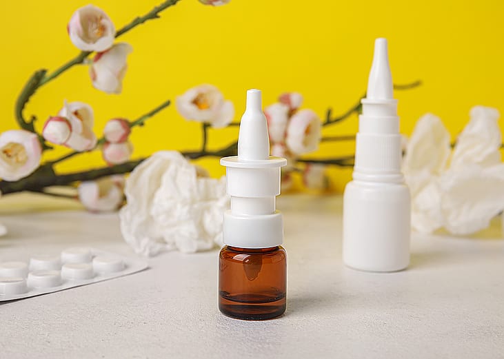 Nasal drops with medicine pills in the background.