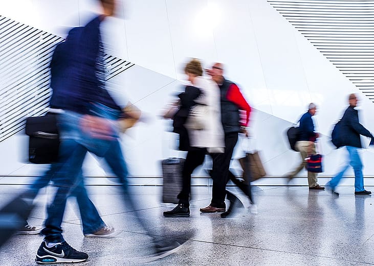 A motion blur shot of passengers walking inside an airport.