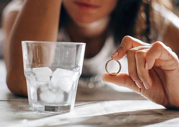 A sad woman holding wedding ring.