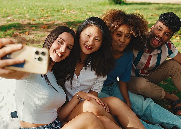 A group of four friends taking a selfie together outdoors.