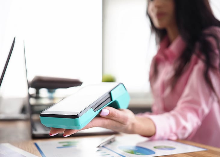 A person holding a banking mobile device in a workplace. 