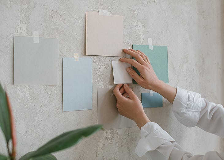 Woman hanging paint color mock ups on a wall.