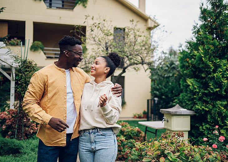 A couple standing outside their new home after moving in. 