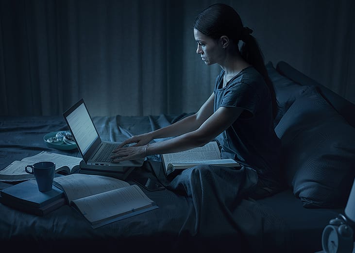 A student pulling an all-nighter for an exam in her bedroom. 