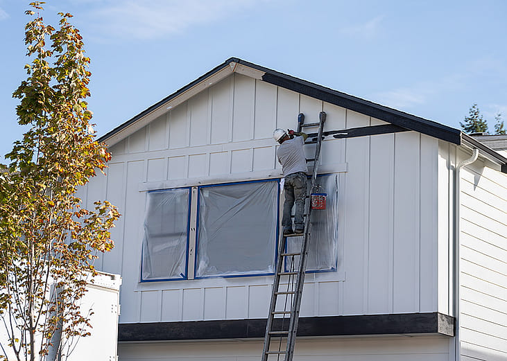 A house painter doing trim work of a house's exterior wall. 