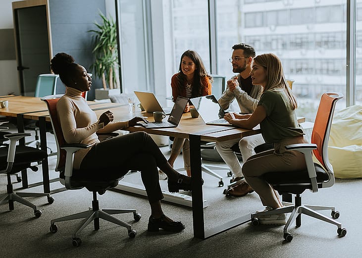 An employee sharing ideas to teammates in a workplace meeting.