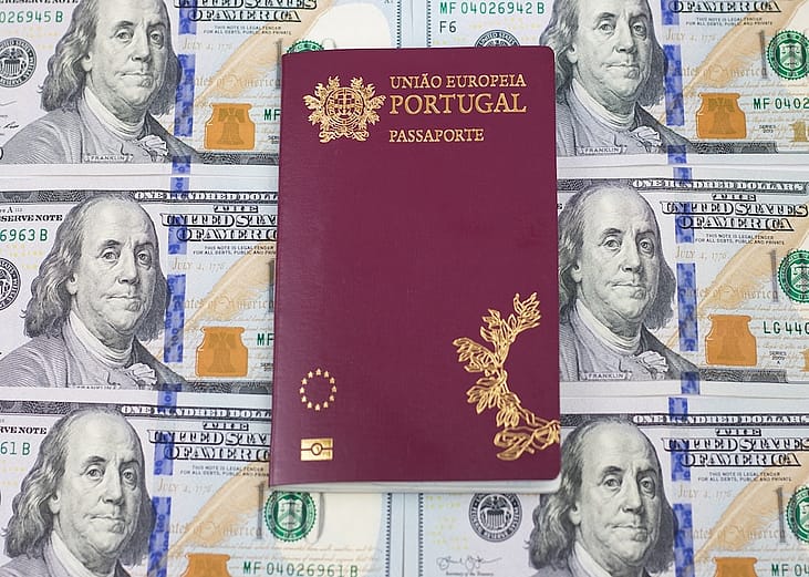 A Portuguese passport on top of one hundred U.S. dollar bills. 
