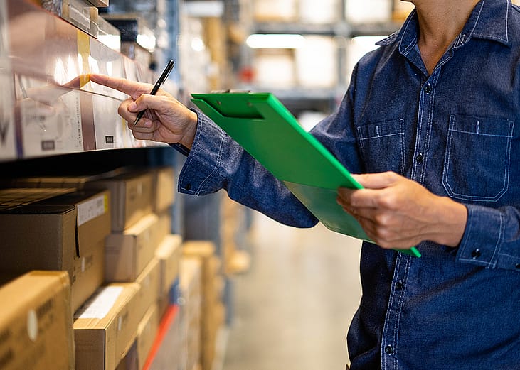 A factory assistant checking stocks for an inventory at a warehouse.