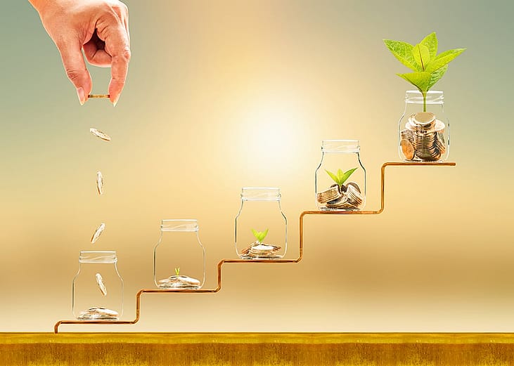 Hand dropping gold coins on jars on a staircase as a concept of financial building.