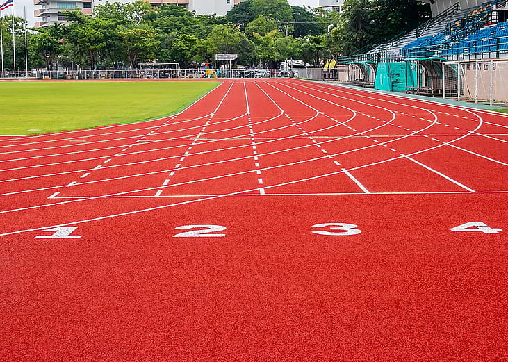 A red running track in an athletic stadium.