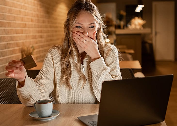 Young woman in shock by credit card information online.
