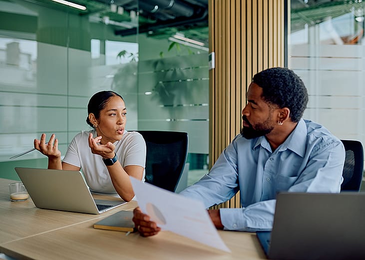 Two business colleagues engaged in discussion in a boardroom.