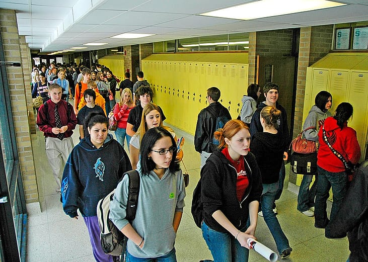 High school students walking along hallways.