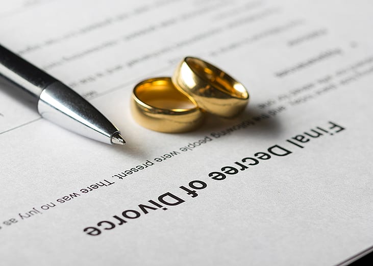 Marriage rings and a pen on top of a divorce decree form. 
