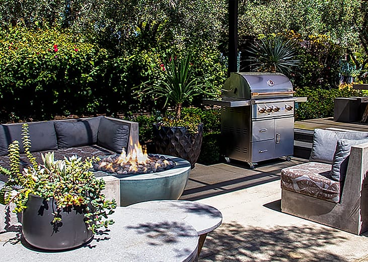 An outdoor entertainment space with gray sofas and a fire pit.