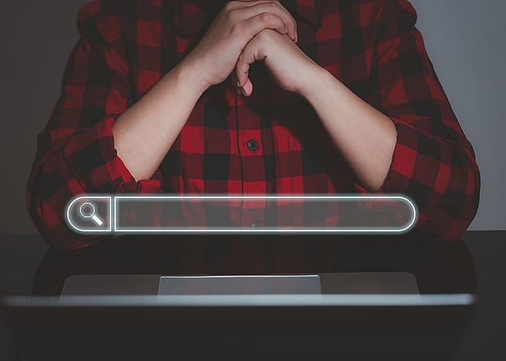 A floating search bar and a data analyst working on search engine concept from a laptop in the background.