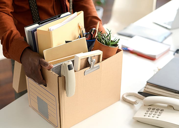 An office worker packing personal office items to a box. 