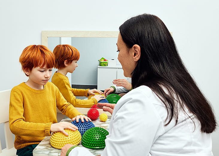 An occupational therapist using sensory integration therapy to a child patient in a clinic.