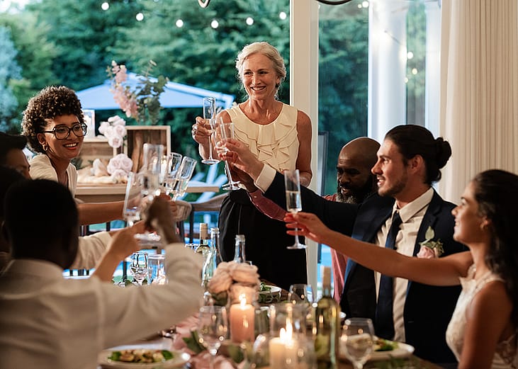 Guests raising glasses during a joyful toast from a wedding reception dinner.