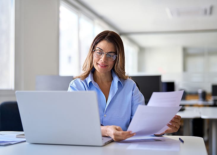 A businesswoman reading tax papers in an office.
