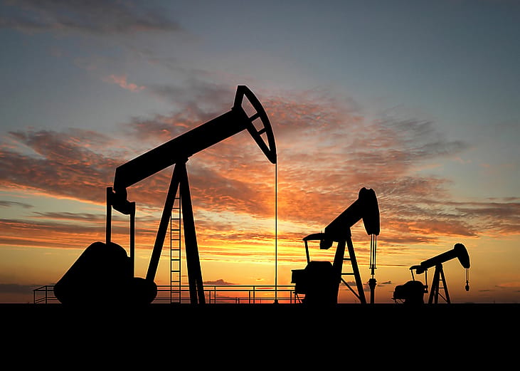 Silhouette of gas pumps machinery during sunset.