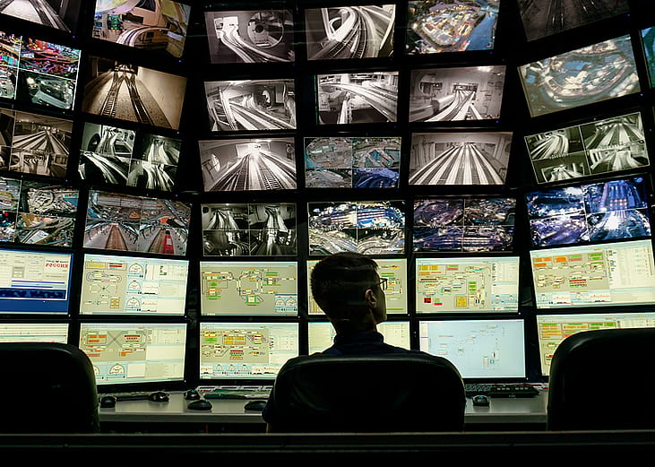 A security staff member overlooking a multiple display monitoring system.