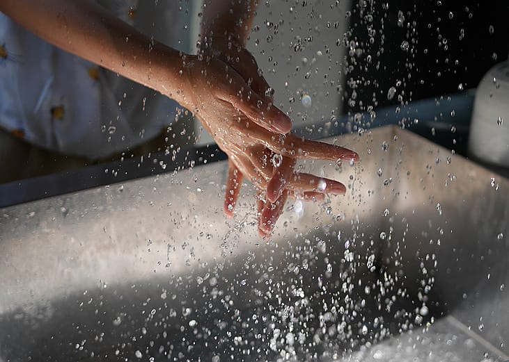 Person washing hands over a sink.