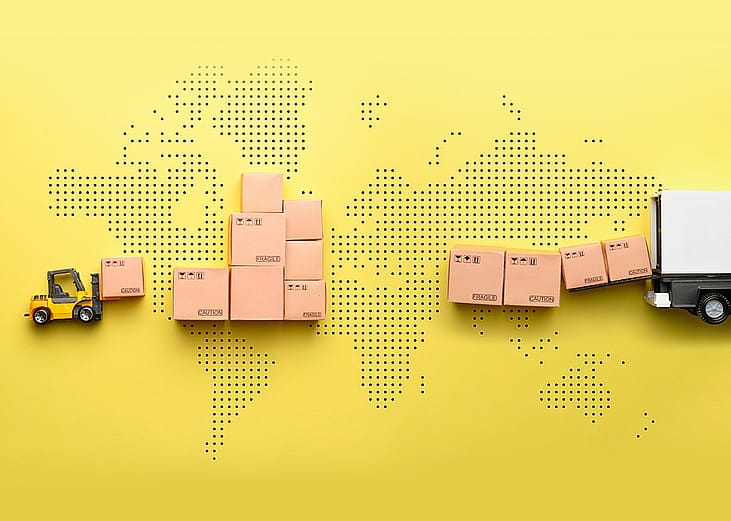 A loader loads goods into a truck against the backdrop of a world map.
