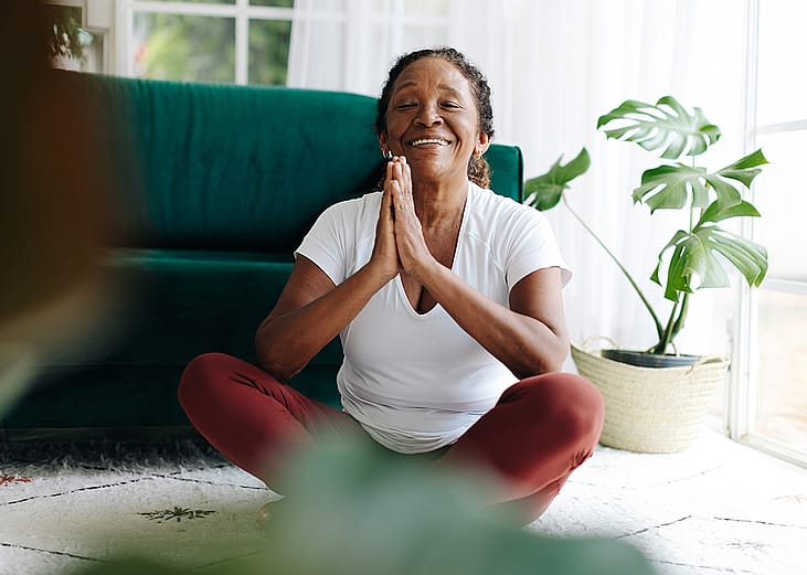 A elderly person practicing meditation in a prayer pose during a yoga session.