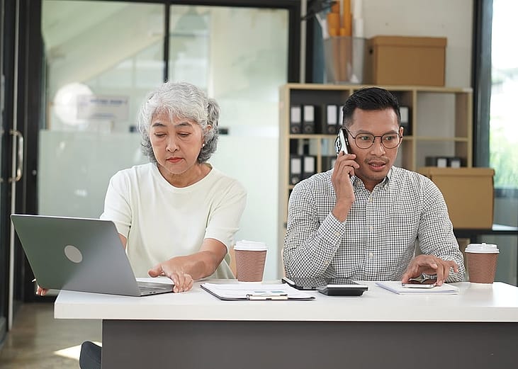 Co-business owners separately talking with customers using different devices.