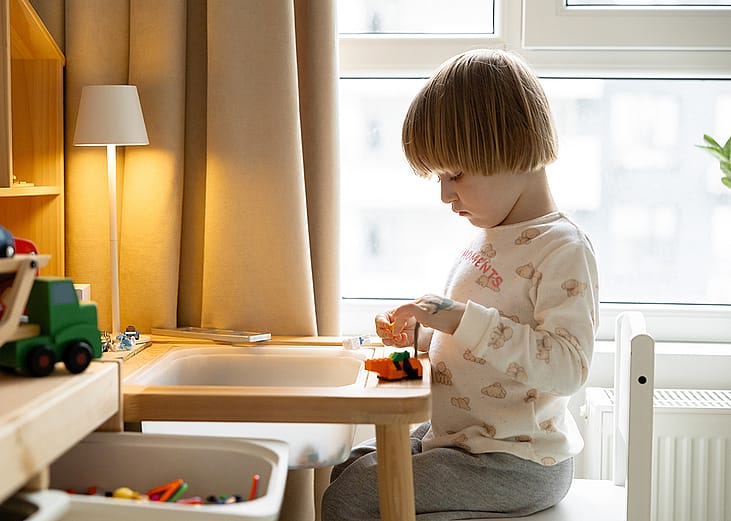 A young boy playing with block toys in the corner of a room.