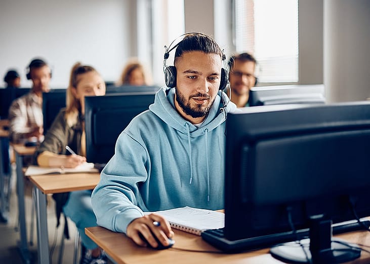 A male university student using a desktop computer during a class.