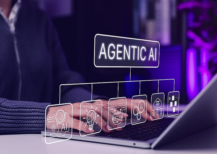 Agentic AI software graphics illustrated over a person using a laptop.