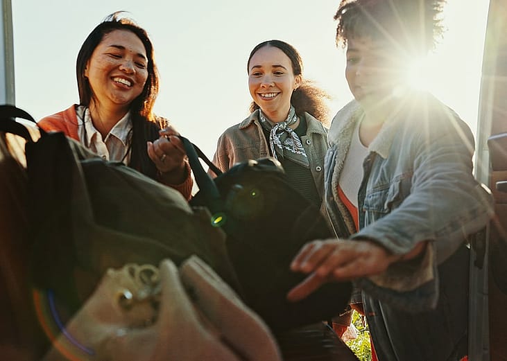 An excited group of friends packing their bags for a roadtrip.