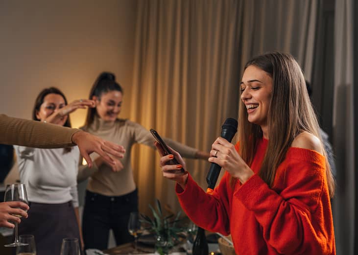 A young woman sings karaoke at a house party.