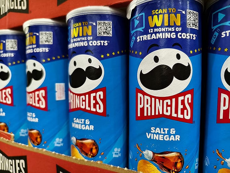 Cans of Pringles on a shelf featuring a QR code for a contest.